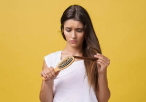 Mujer con cabello fino mostrando un tratamiento efectivo para la caída del cabello, incluyendo remedios naturales para fortalecer y nutrir el cabello
